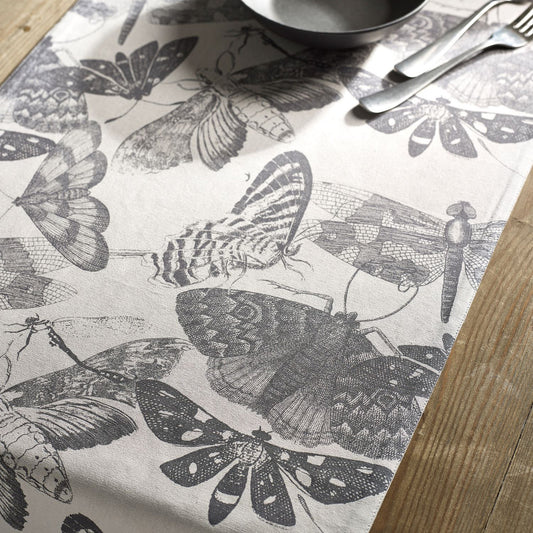 Monochrome table runner with detailed illustration of moths and butterflies, in dark grey on a natural background, from Kew Gardens available from Vinegar Hill.