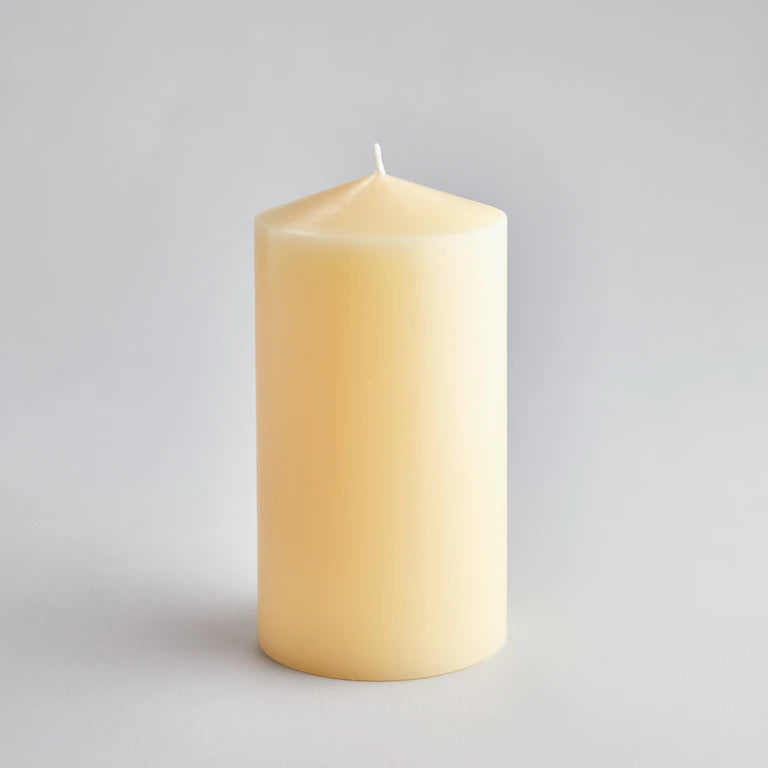 large cream coloured pillar candle poured to a tapered head with a white wick.