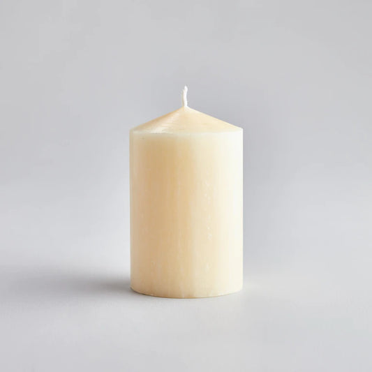 medium cream coloured pillar candle poured to a tapered head with a white wick.