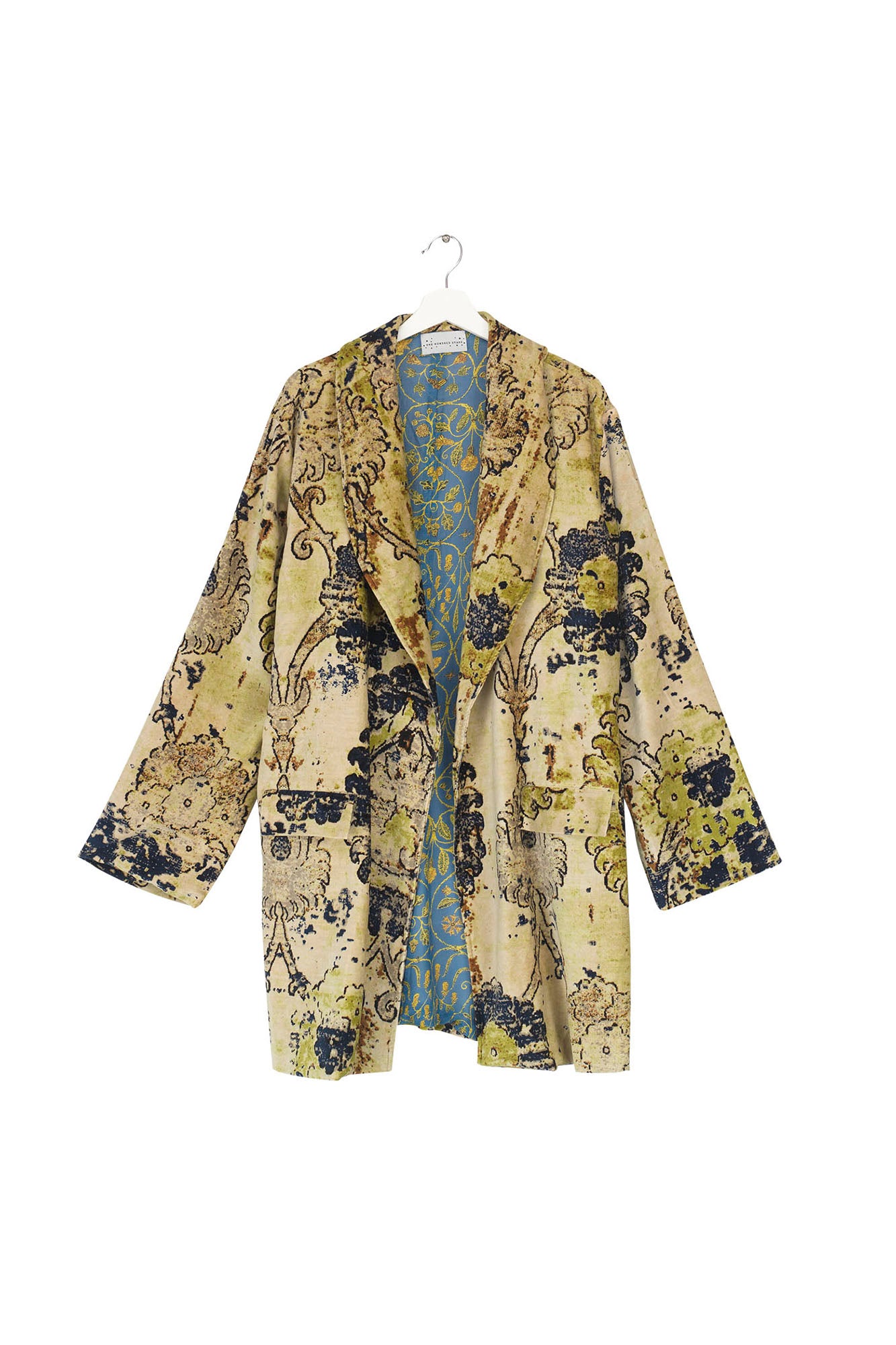 An image showing the front of the luxurious velvet One Hundred Stars jacket, from Vinegar Hill. The jacket is hanging from a white coat hanger and shows the patterned lining. The jacket is patterned in muted tones of taupe and green with black line drawings.